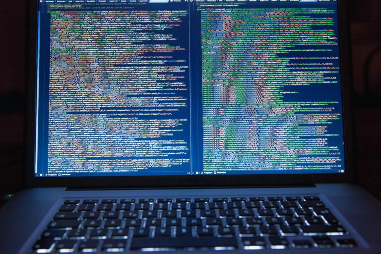 Kódsorok egy laptop képernyőjén, sötét háttér előtt
